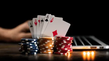 A man celebrating a winning moment on his laptop while gaming symbols float around him, capturing the excitement of 77ABC games.